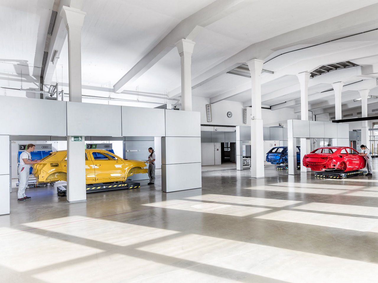 The image shows a state-of-the-art production hall with the bodywork of Audi cars on driverless transport systems.