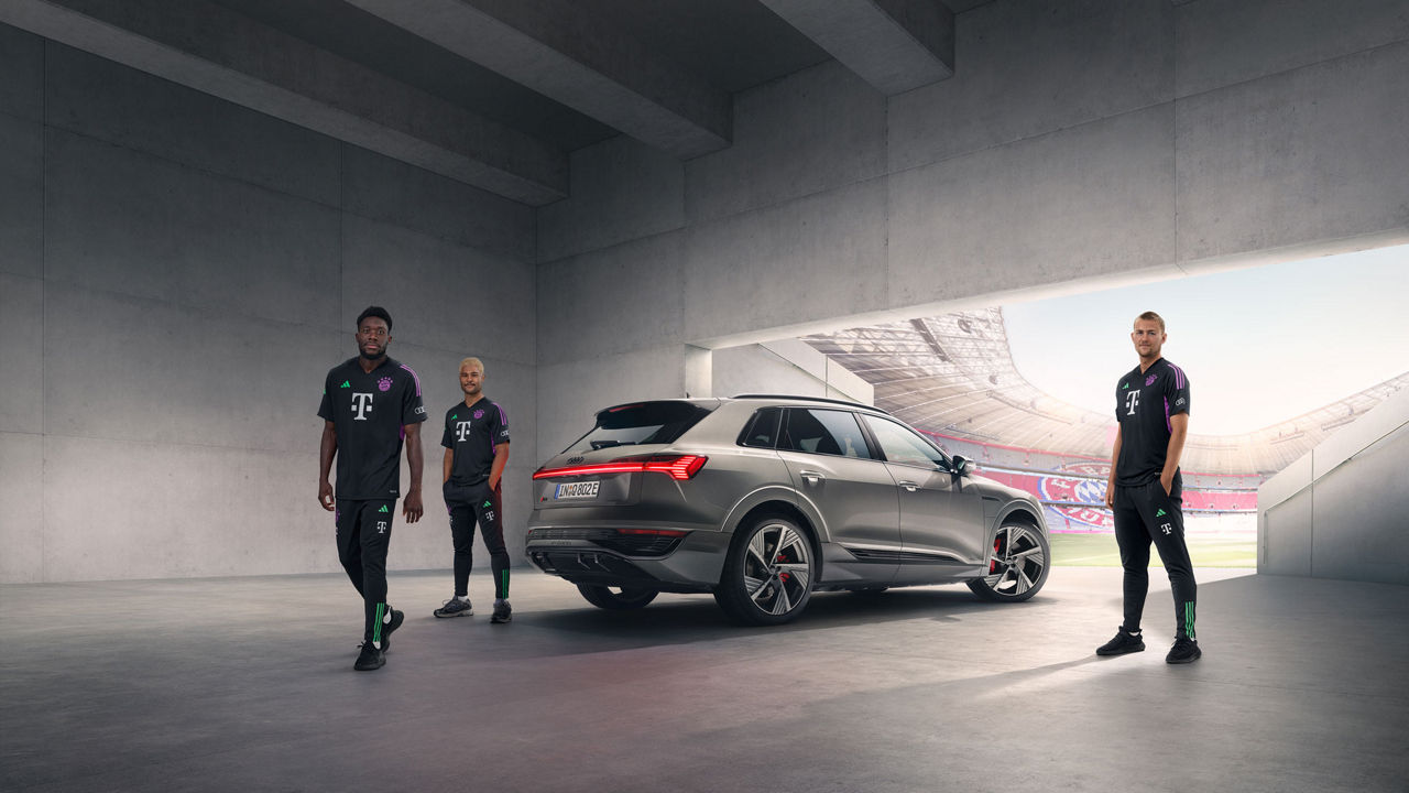 Ein silberner Audi Q8 e-tron umringt von FC Bayern Spielern am Einlauf der Allianz Arena