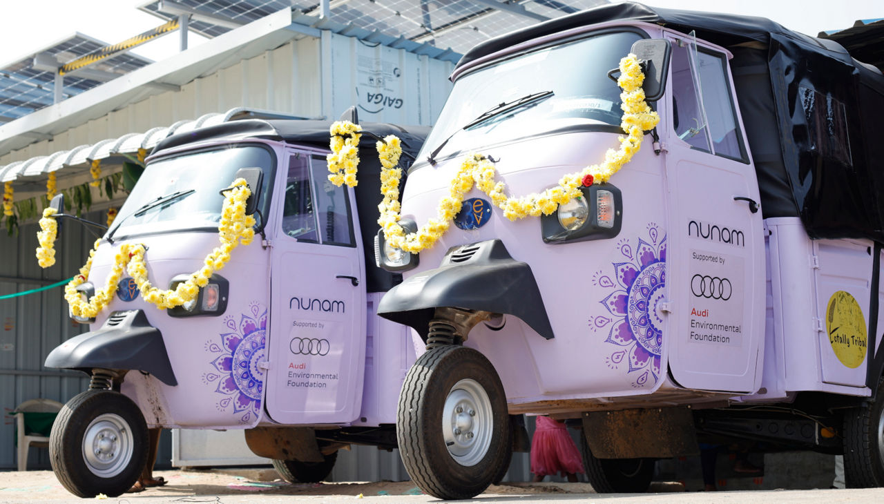 Two Nunam vehicles are parked in front of a building that has solar panels on its roof