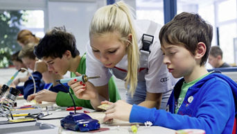 An Audi employee works with children on model cars