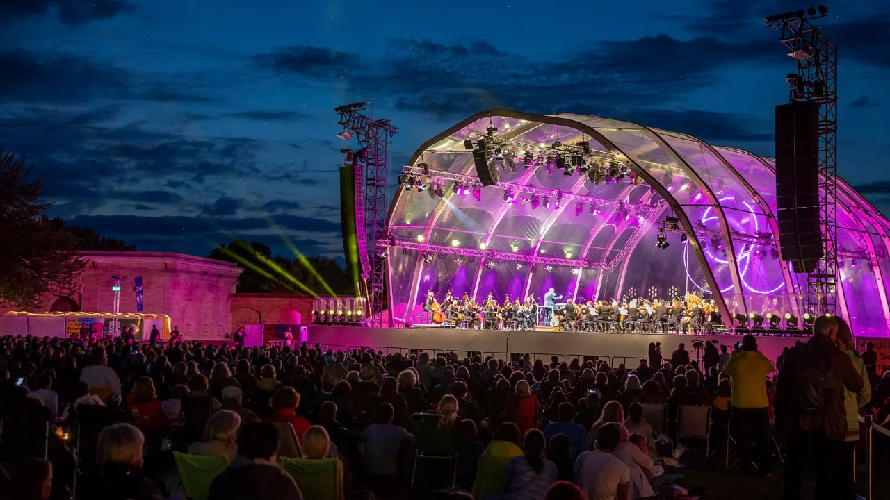 Many people sit in front of an illuminated stage at night
