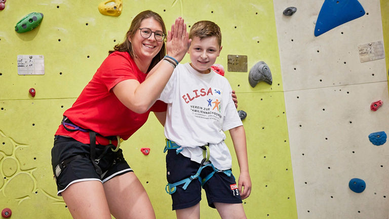 Woman with child in front of climbing wall.