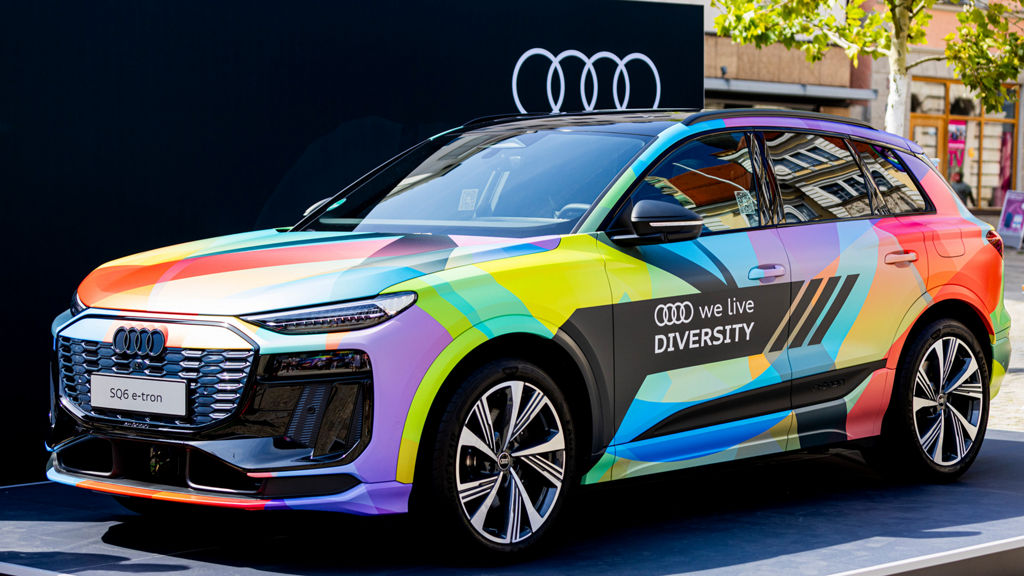 Der bunt lackierte Diversity Audi steht vor einem schwarzen Hintergrund mit Audi Logo
