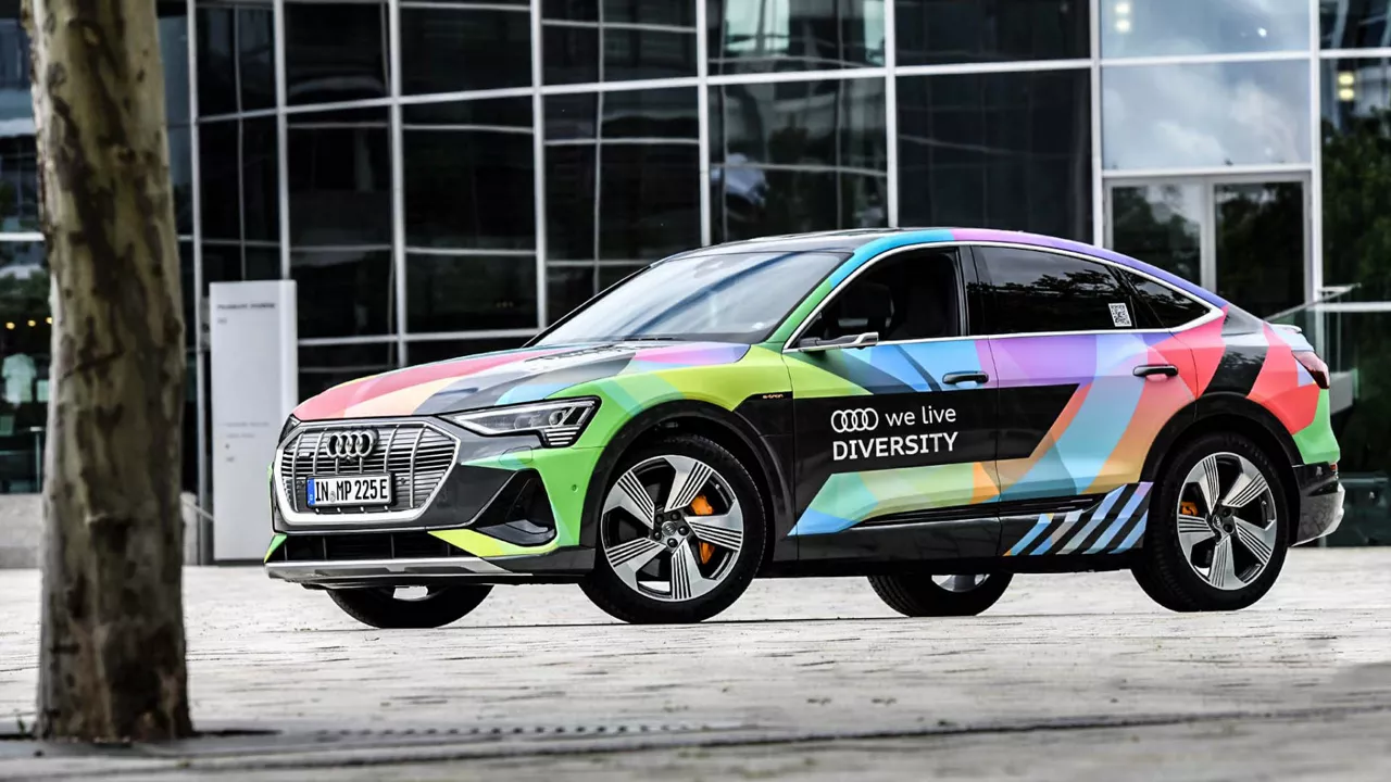 Ein bunt beklebtes Audi Modell mit der Aufschrift "We live Diversity" neben den Audi Ringen