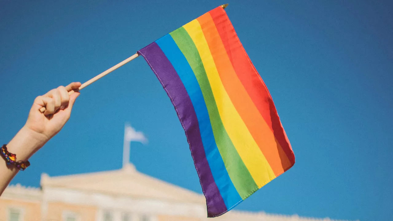 Eine Regenbogenflagge wird in einer Hand gehalten