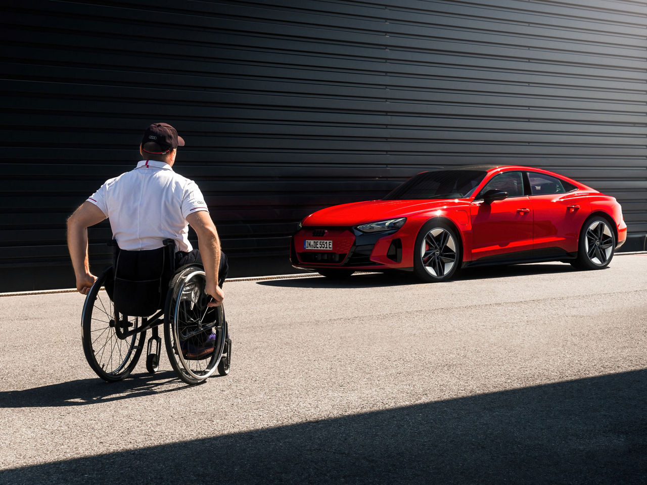 Man in wheelchair approaches a red Audi e-tron GT