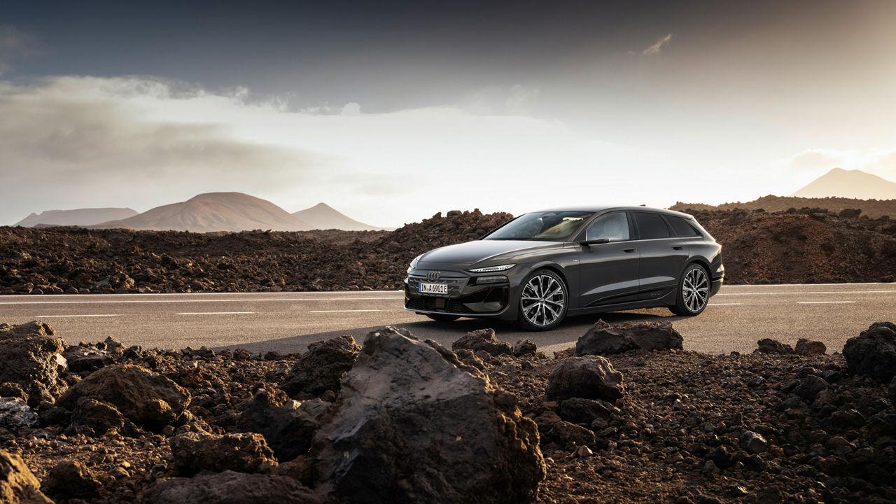 Audi A6 Avant e-tron performance steht auf einer Straße vor einer Bergkulisse. Neben der Straße liegen Felsen und Geröll.