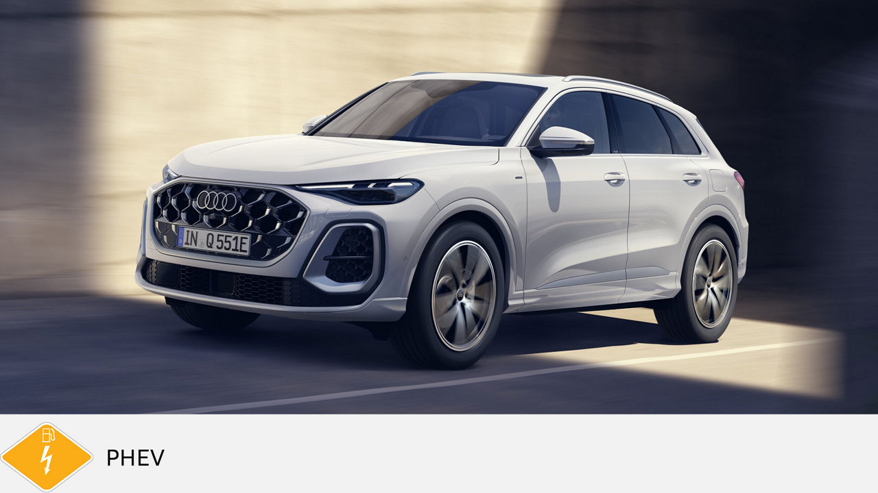 Weißer Audi Q5 Plug-in-Hybrid fährt durch eine sonnige Stadtumgebung, PHEV-Symbol unten links.