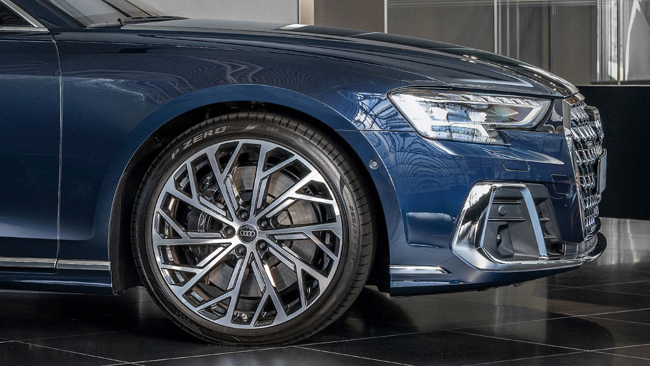 Close-up of a detailed, shiny aluminium rim of an Audi A8L with sporty tyres.