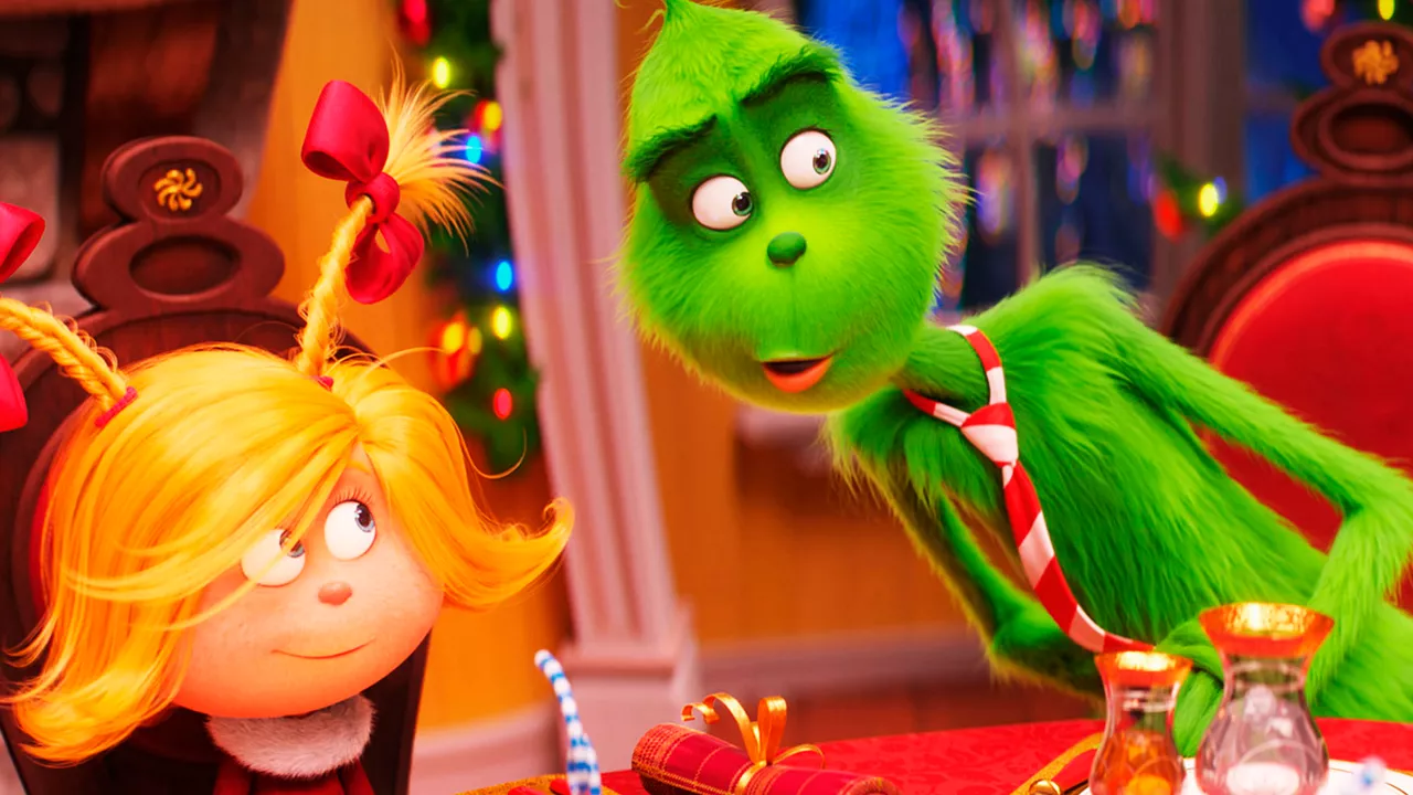 Der giftgrüne Grinch unterhält sich angeregt mit mit einem kleinen Mädchen.