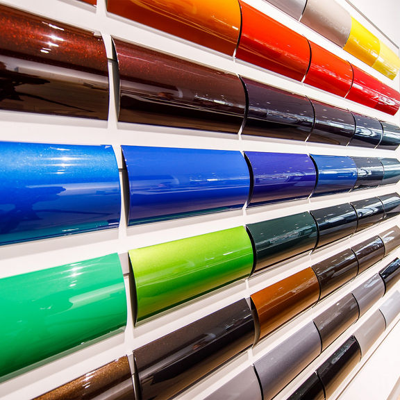 Several rows of glossy lacquer patterns in different colors on a white wall.