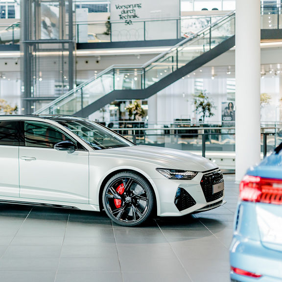 Side view of a white Audi RS 6 Avant with red brake calipers in a modern showroom.