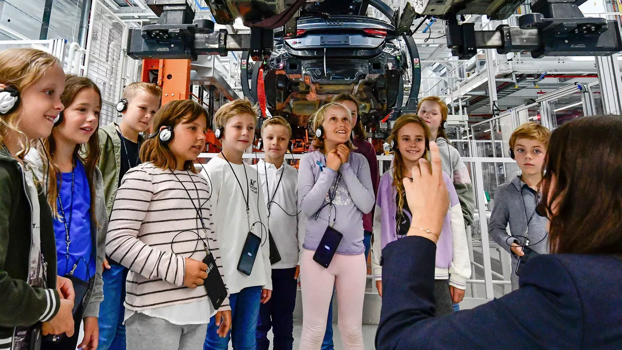 Children look at the body of an Audi from below during a guided tour.