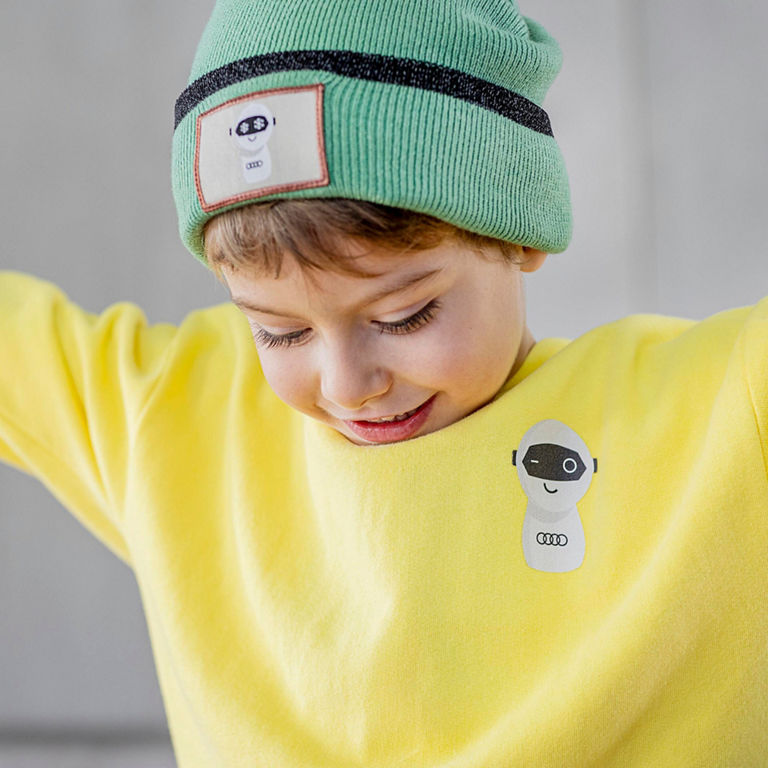 Close-up of an an child with an Audi pullover and beanie.