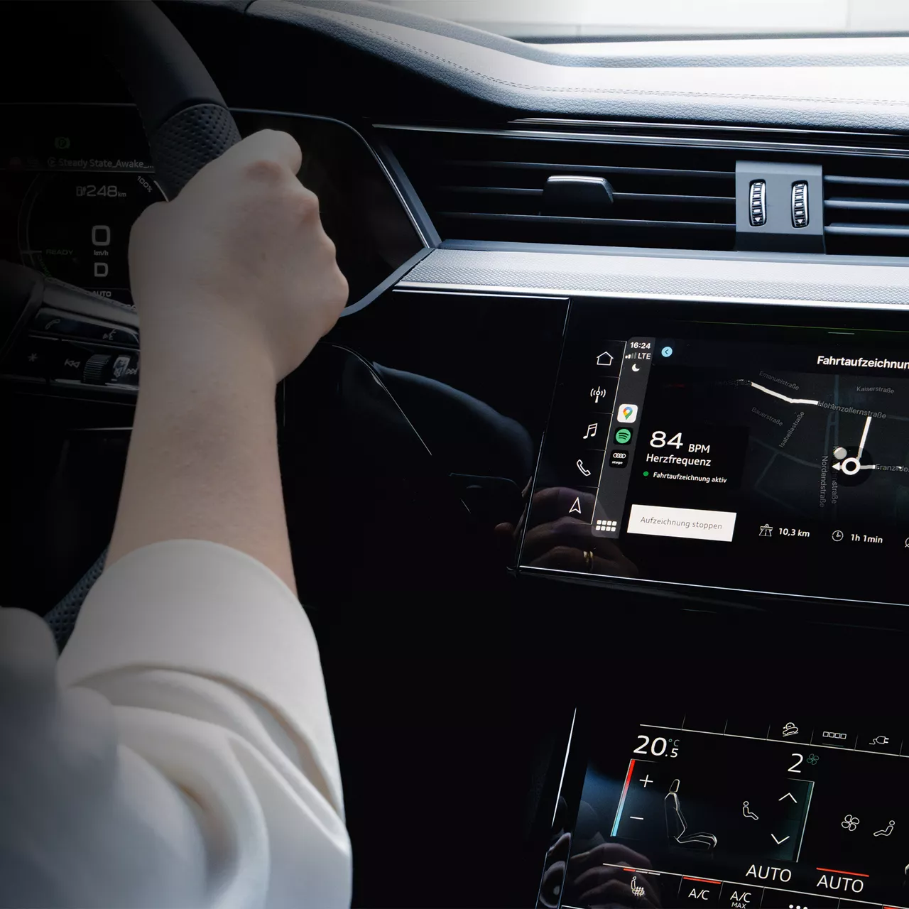 A vehicle dashboard with digital displays, including an 84 BPM heart rate monitor, navigation system and climate settings, while one hand holds the steering wheel.