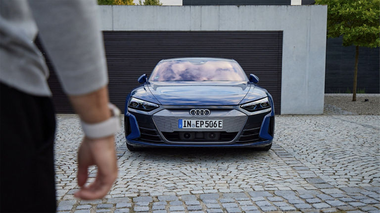 Eine Person steht vor einem blauen Audi e-tron GT quattro