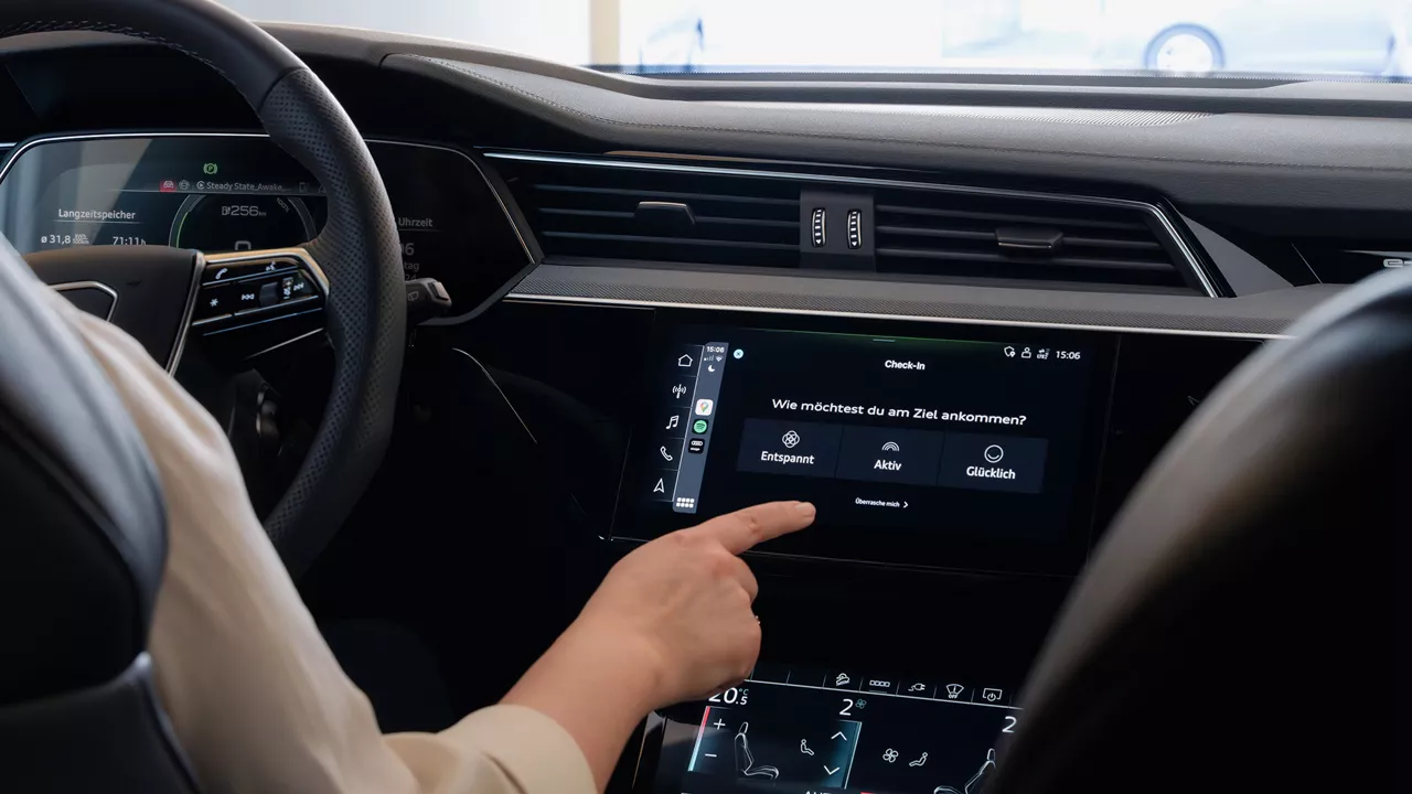 Jemand sitzt in einem Audi Modell und gibt im Display ein, wie er am liebsten sein Navigationsziel erreichen möchte (entspannt, aktiv oder glücklich)  