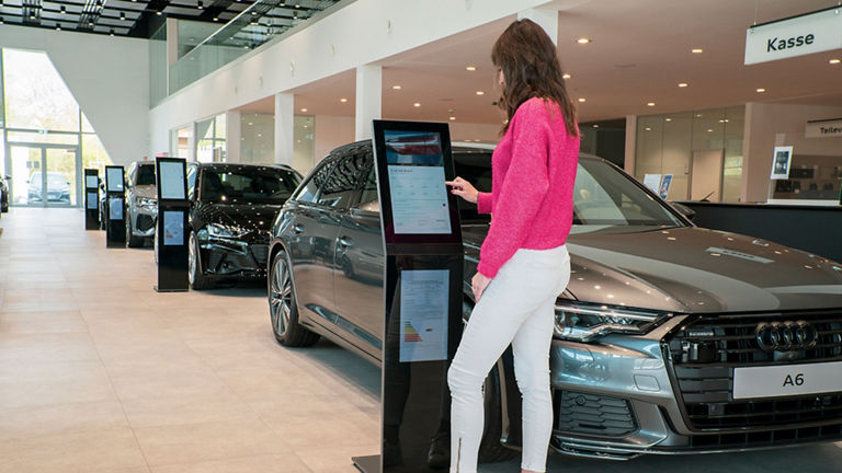 Frau bedient vor einem Audi einen Multi Touch Table