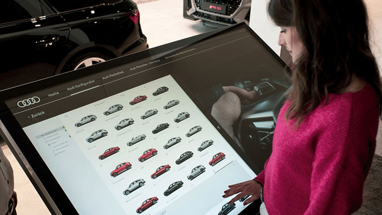 Frau steht an einem Multi Touch Screen