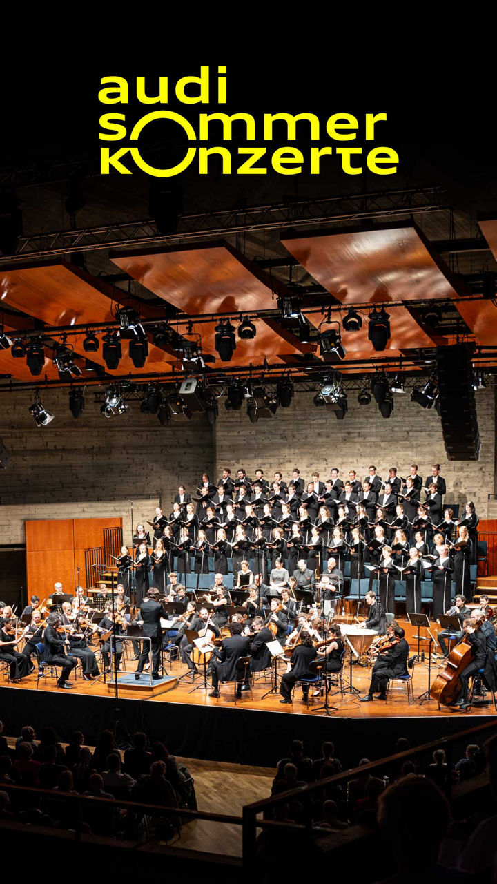 Ein Orchestra in schwarzem Outfit befindet sich auf einer Bühne