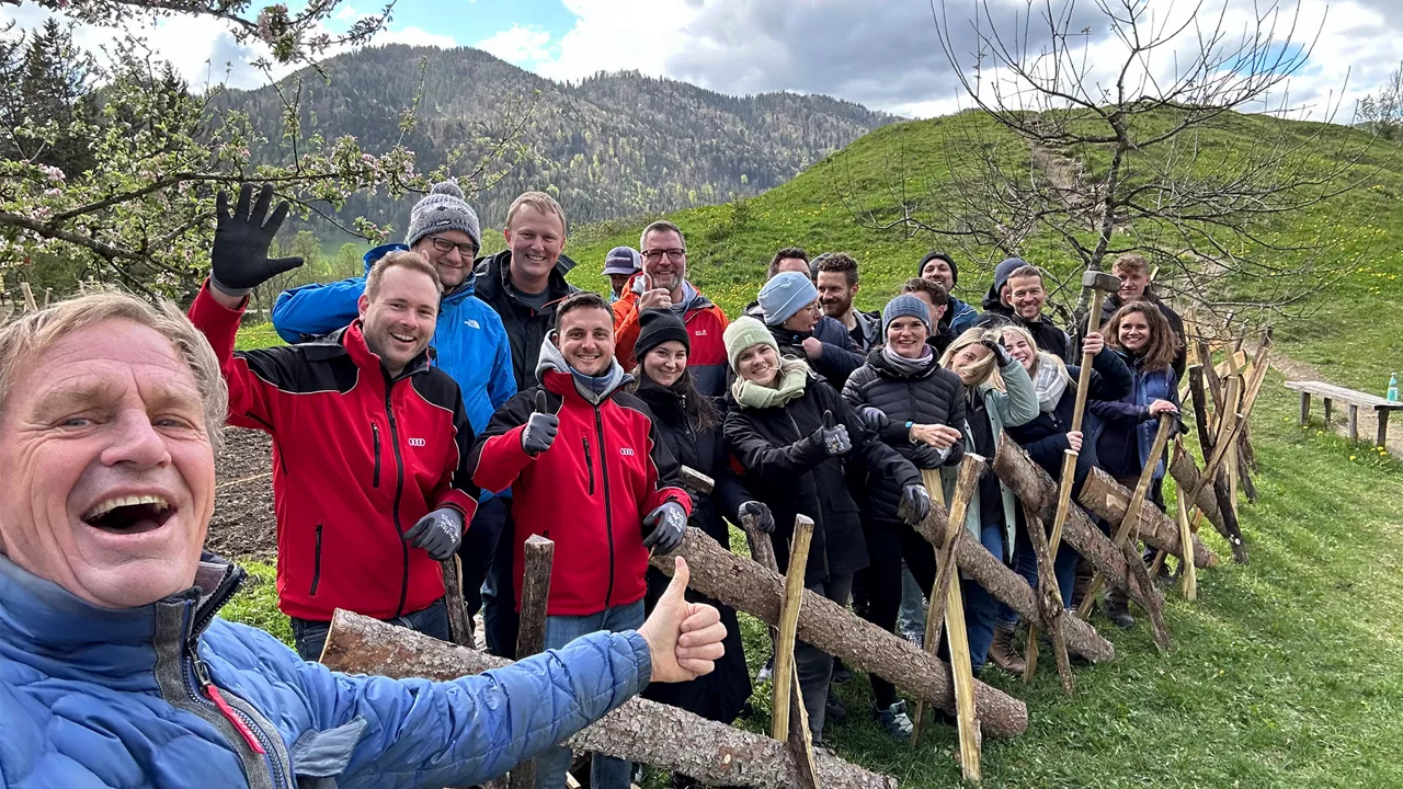Team posiert für ein Gruppenbild vor einem selbstgebauten Zaun