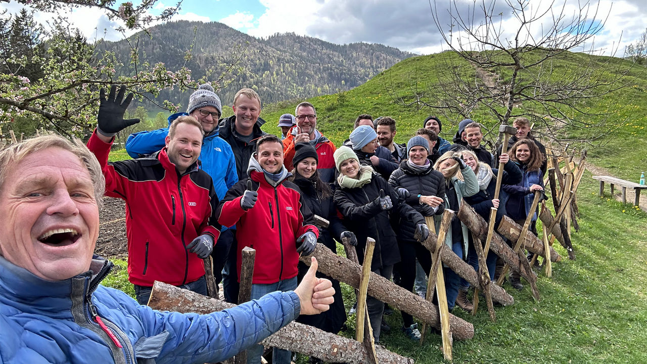 Gruppe von Helfern posieren für ein Gruppenbild vor einem selbstgebauten Zaun
