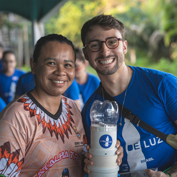Two people smiling for a picture, posing with a light source.