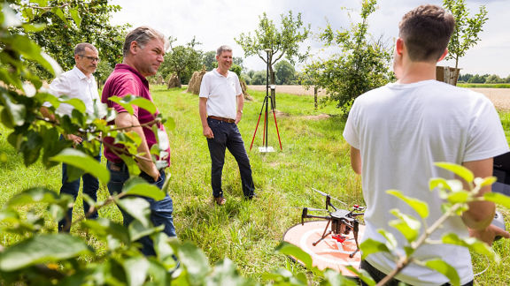 A group of men standing outdoors with a drone