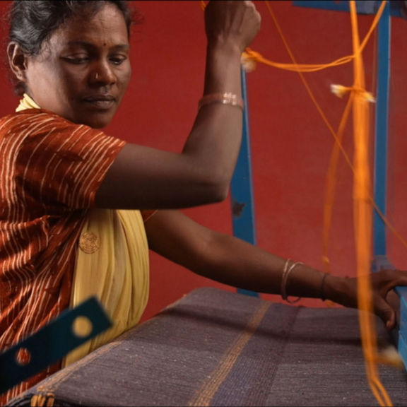 A woman in close-up at work on a loom.