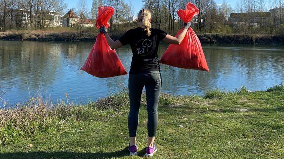 Frau hält zwei volle Müllsäcke in die Luft