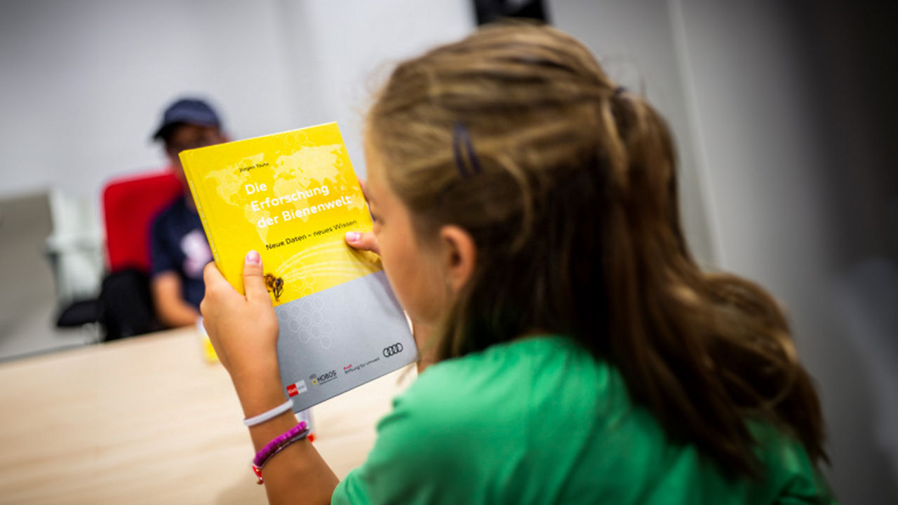 A girl is reading a book about researching the world of bees