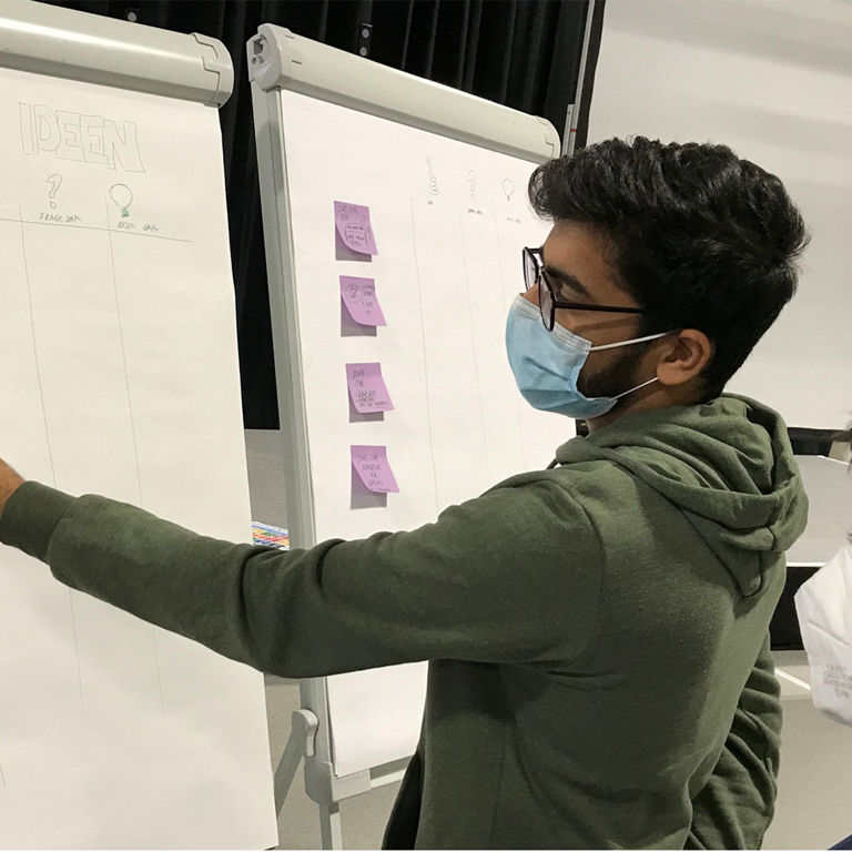 Mann schreibt etwas auf ein Whiteboard