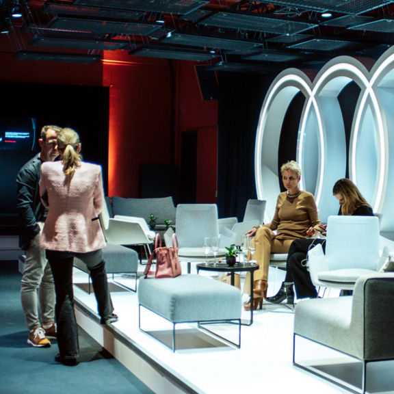 Speakers on stage in front of an Audi logo