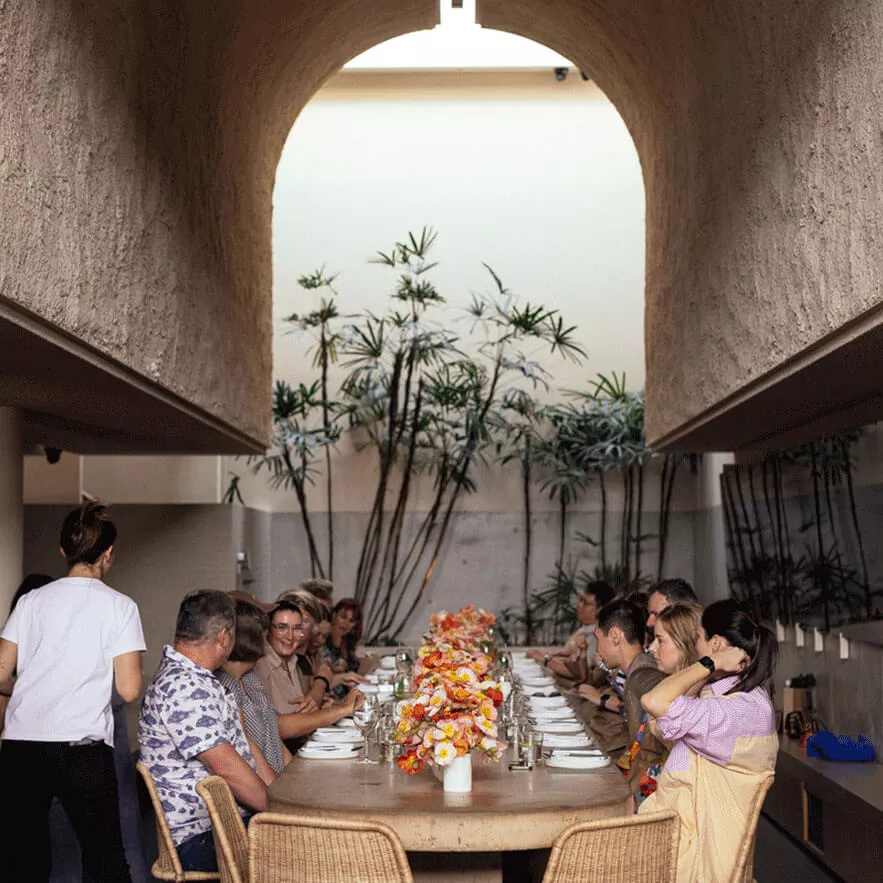 A diverse group of individuals engaged in conversation while seated around a long table in a collaborative setting.