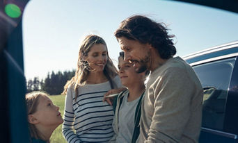 Family of 4 standing around their Audi E-Tron