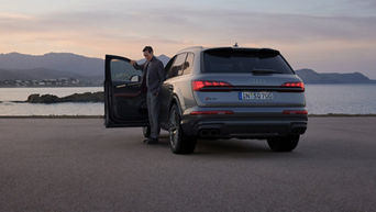 A 2024 Audi Q7 parked, framed by tranquil water in the background, exemplifying sophistication amidst a coastal landscape.