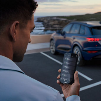 Mann mit Handy in der Hand steht vor einem Audi Q4