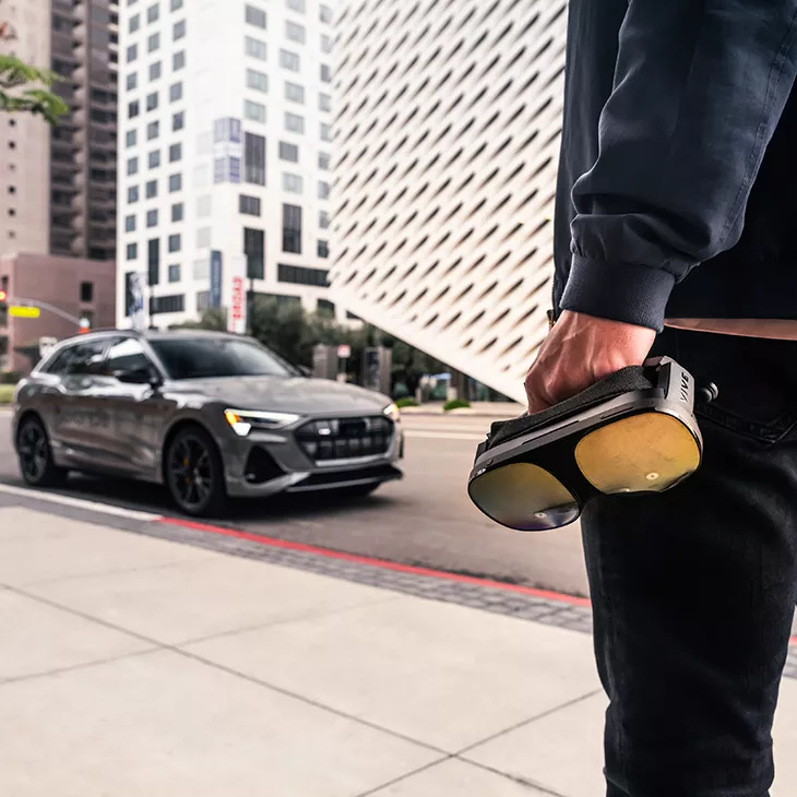 Ein Mann sitzt in einem Audi auf der Rückband und trägt eine VR-Brille