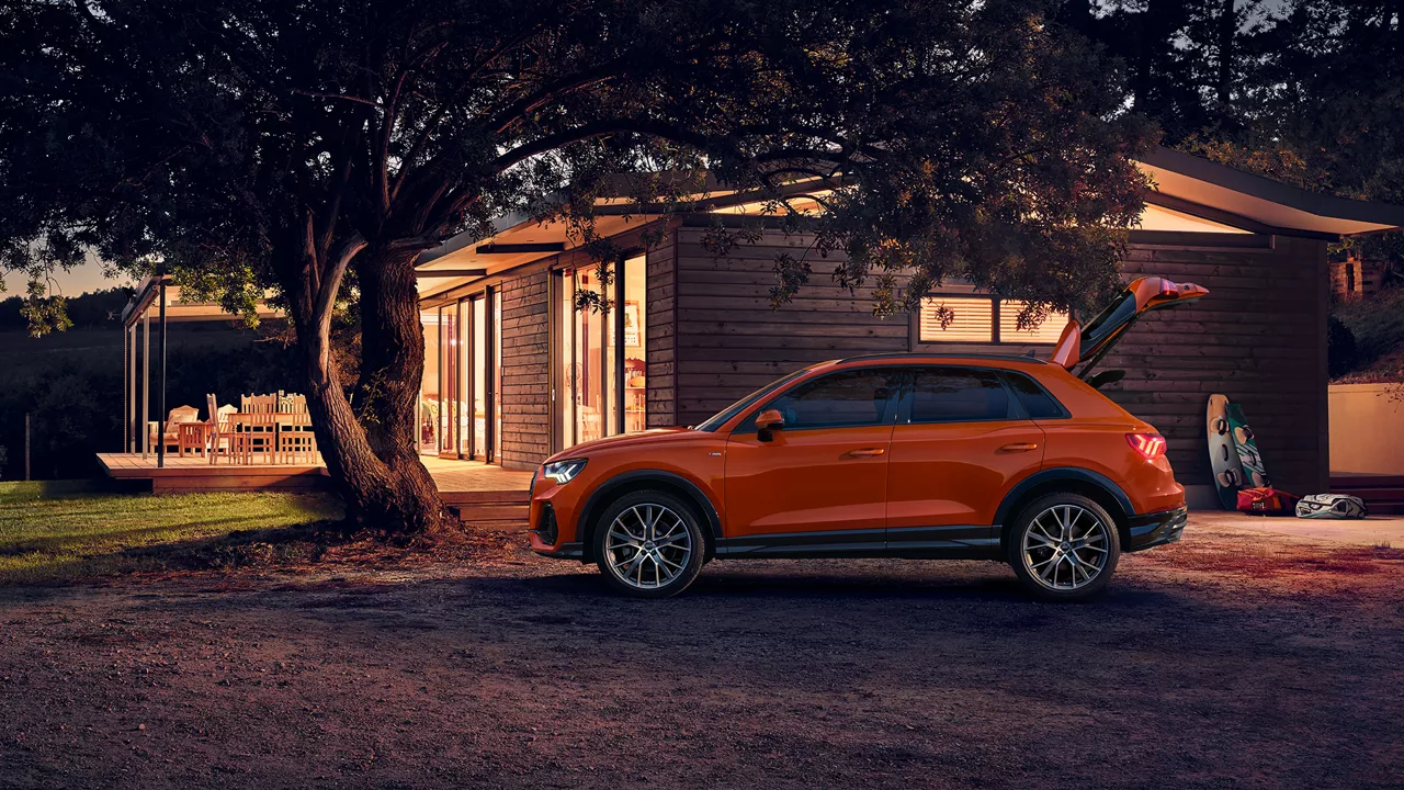 Ein orangener Audi vor einer Holzhütte