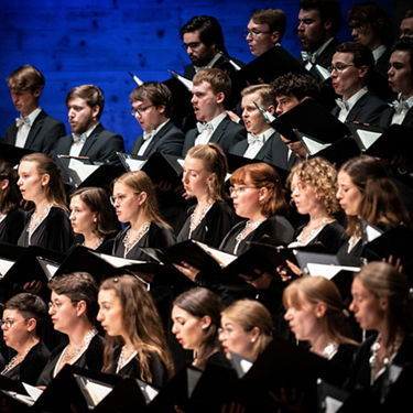 Audi Jugendchorakademie bei einem Auftritt. Junge Menschen mit Songbüchern in der Hand beim Singen.