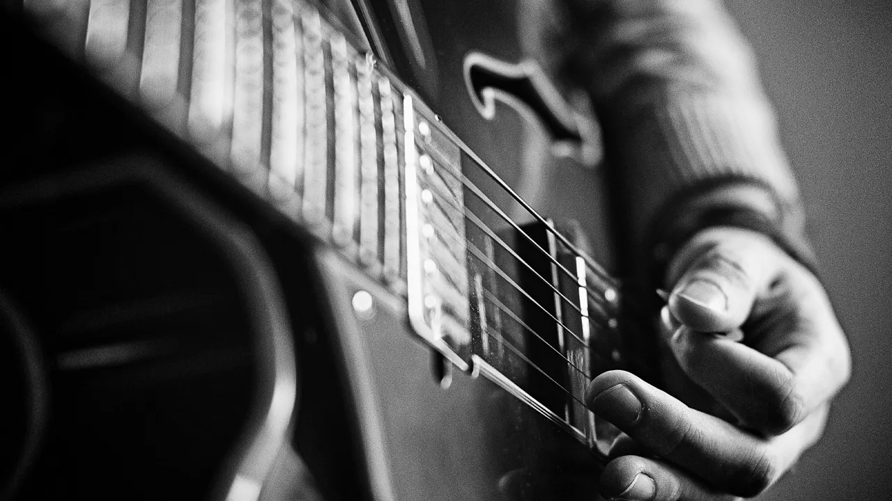 Nahansicht Person nutzt Plektron auf einer Gitarre