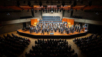 Konzertsaal mit Bühne im Mittelpunkt, auf der die Audi Bläserphilharmonie spielt