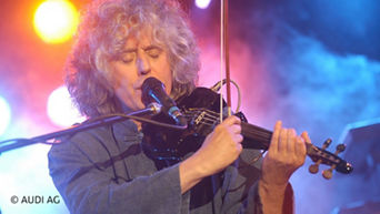 Mann spielt Geige und singt ins Mikrofon
