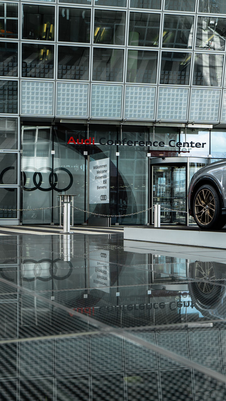 Eingang des Audi Conference Center, ein graues Audi Modell steht vor dem Eingang