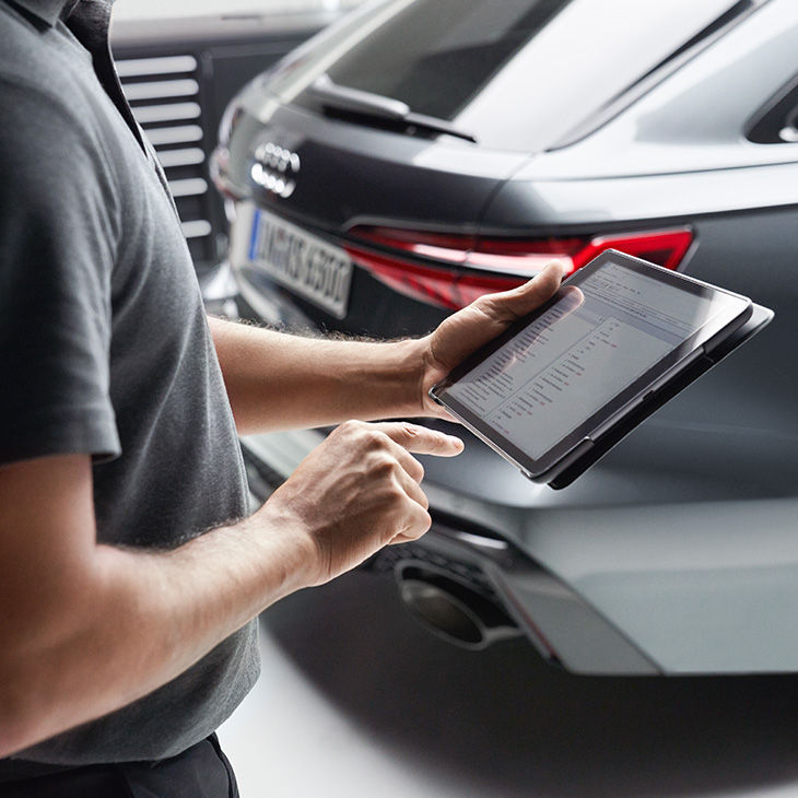 Ein Mann steht mit einem Tablet vor einem Audi