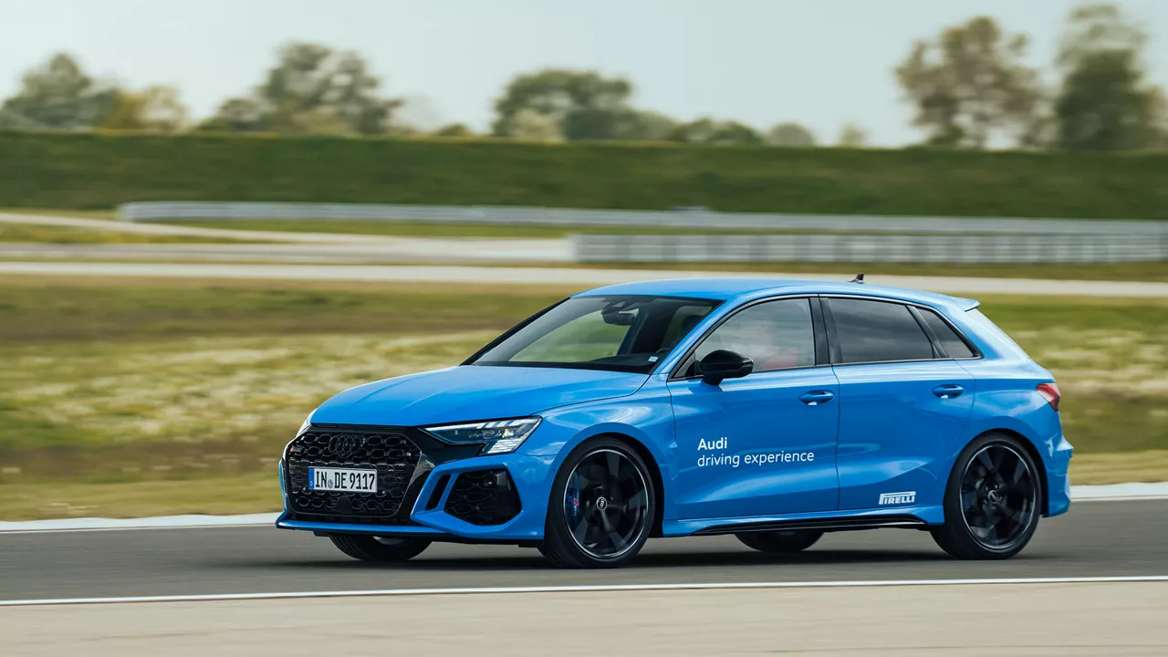 Ein blauer Audi RS 3 Sportback in voller Fahrt auf einer Rennstrecke