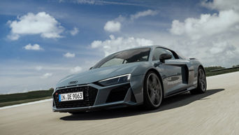 Mattgrauer Audi R8 Coupé V10 performance quattro auf Rennstrecke bei blauem Himmel mit wenigen hellen Wolken.