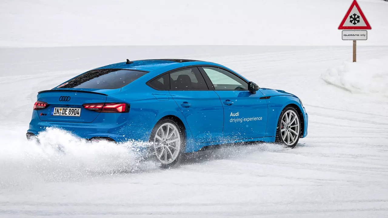 Hellblauer Audi RS 5 Sportback driftet im Schnee