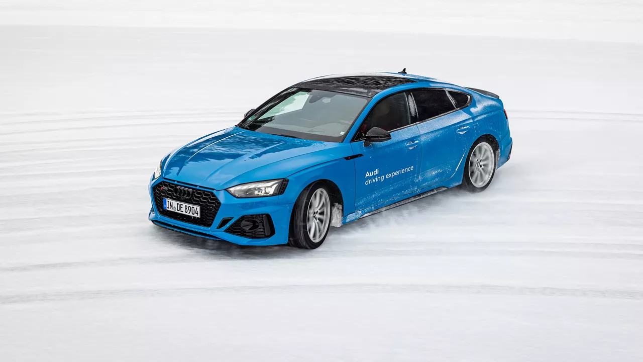 Hellblauer Audi RS 5 Sportback driftet im Schnee