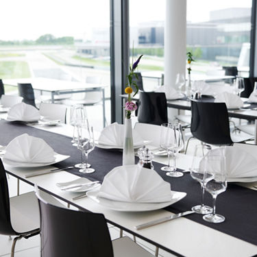 Elegant gedeckter Tisch mit weißen Servietten und einer Blume im Audi-Fahrerraum